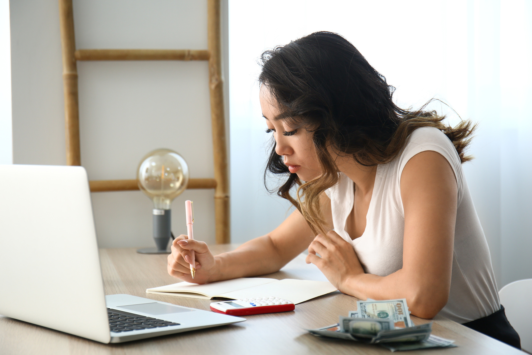 Asian Woman Counting Money at Table